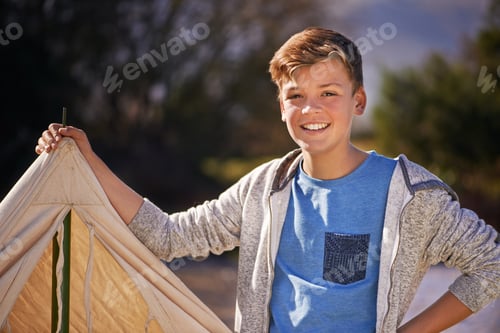 Preview: Camping is the best. Shot of a young boy putting up his tent on a camping trip.