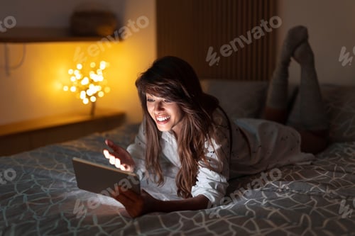 Preview: Smiling Woman Using Tablet Lying on Bed