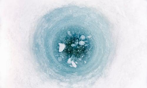 Preview: High angle close up of ice-fishing hole on frozen lake in Vasterbottens Lan, Sweden.