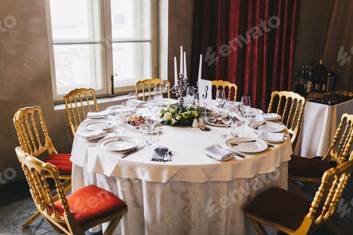 Preview: Round table with many chairs around served for many people in retro style with white tablecloth