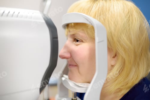 Preview: Portrait of mature woman during visit to optometrist for microscopic analysis of eyelids, sclera etc
