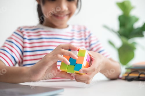 Preview: Asian little cute girl holding Rubik's cube in her hands.