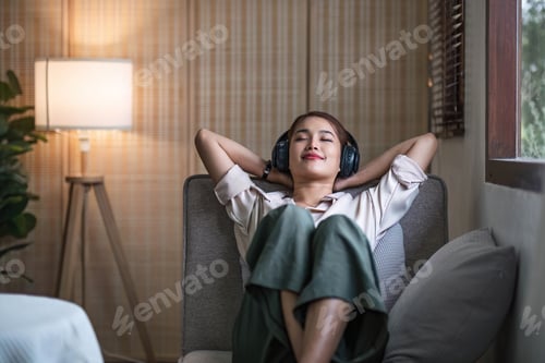 Preview: Happy woman relaxing in her sofa at home, Smiling girl is listening to music with headphones and