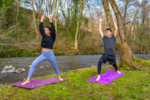 Preview: Yoga instructors performing warrior pose by the river in nature