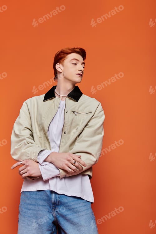 Preview: Emotional young man poses in stylish outfit against vibrant orange background