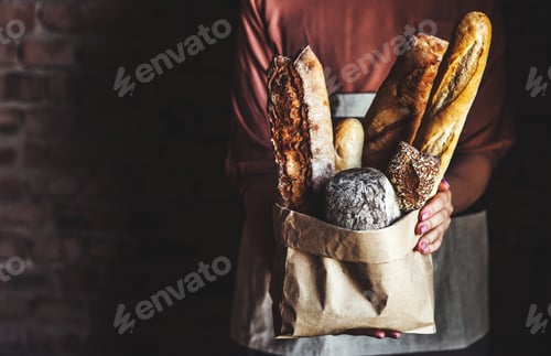 Preview: French baguettes in female hands on a black background. homemade baking