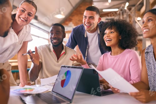 Preview: Multi-Cultural Business Team Meeting Around Desk In Modern Open Plan Office Discussing Documents