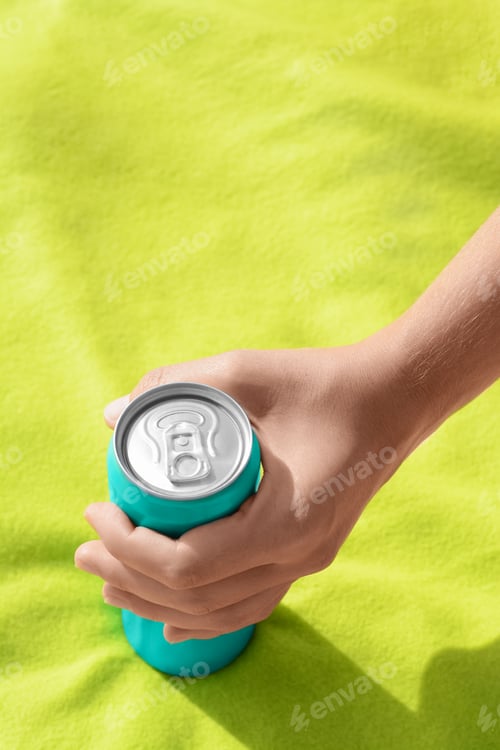 Preview: Woman holding aluminum can with beverage on yellow blanket, closeup