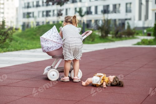 Preview: Toddler girl playing with toy stroller with doll. Two years old. Developmental milestones.