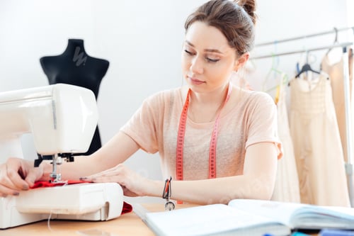 Preview: Concentrated woman seamstress sews on sewing machine