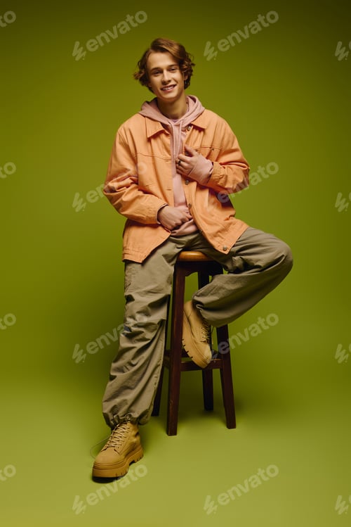 Preview: Young man showcases trendy fashion against vibrant solid background in stylish pose