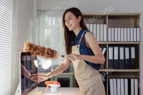 Preview: Woman cleaning office desk, dusting computer monitor