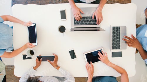 Preview: Overhead Shot Of Business Team Meeting Around Table Working On Digital Devices