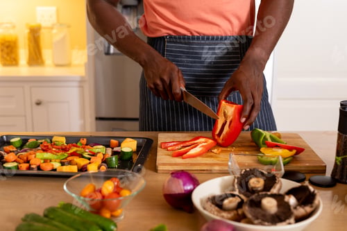Preview: Midsection of african american man chopping vegetables in kitchen
