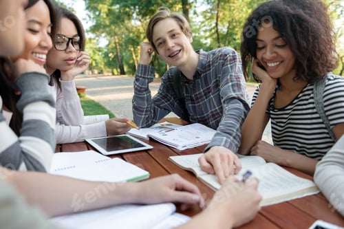 Preview: Young students sitting and studying outdoors while talking