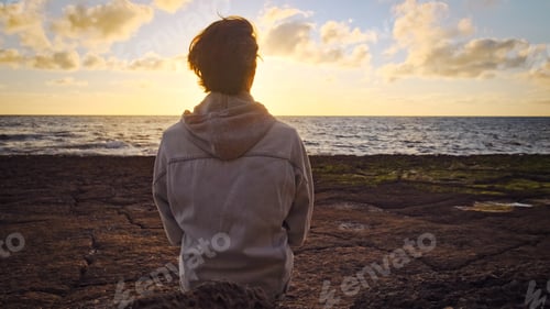 Preview: Man on a beach is looking distance during beautiful summer sunset.