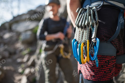 Preview: Instructor with harness and carabiners climbing rocks with seniors, active lifestyle.