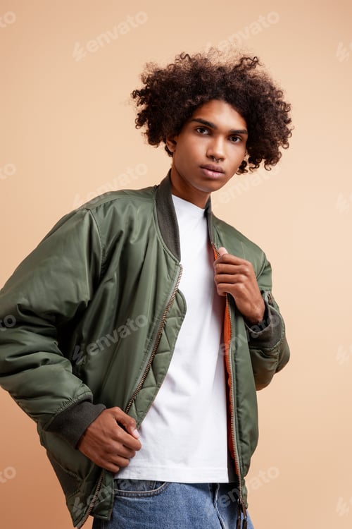 Preview: Pensive, fashion African American young man with piercing in nose wearing stylish green jacket