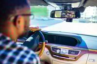 Preview: african american man sitting in a car and adjusting rearview mirror looking to back
