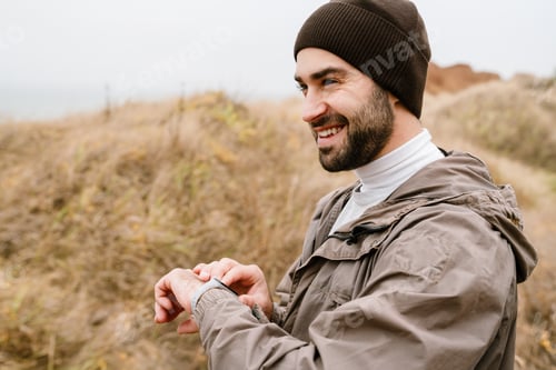 Preview: Happy handsome man smiling and using smartwatch while working out