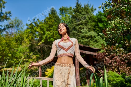 Preview: pleased authentic style indian woman with closed eyes enjoyment walk in summer park