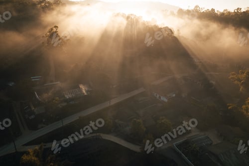 Preview: Aerial view of forest and mountain in fog with golden sunbeams at sunrise