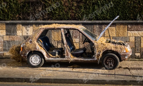 Preview: Metal broken car without doors covered with hay