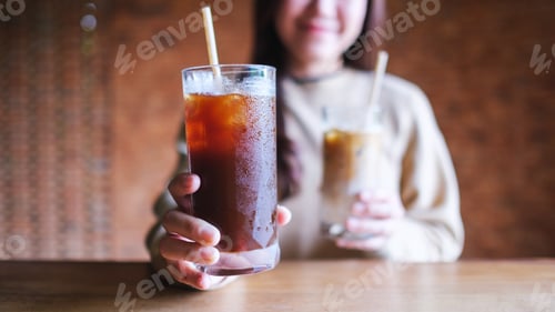 Preview: Closeup image of a young woman holding and serving two glasses of iced coffee