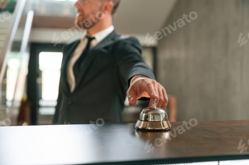 Preview: Standing, using hotel desk bell. A man in a black jacket at the hotel reception