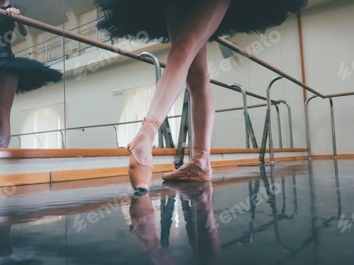 Preview: Ballerina in ballet pointe shoes stretches on barre. Woman practicing in studio