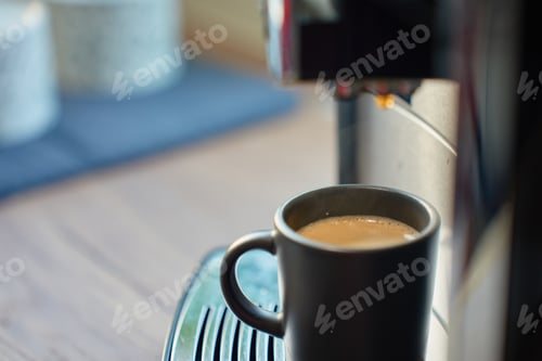 Preview: Black cup with fresh espresso on coffee machine drip tray. Morning coffee