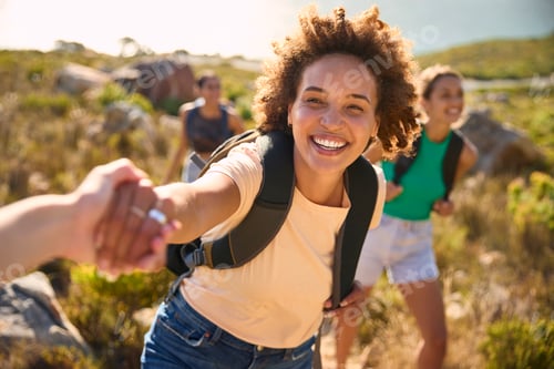 Preview: Group Of Female Friends With Backpacks Helping Each Other On Hike In Countryside On Coastal Path