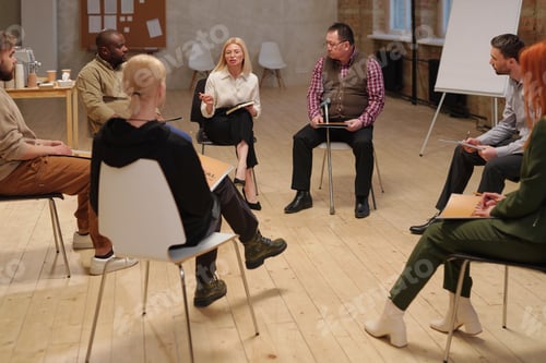 Preview: Large group of contemporary people with psychological problems sitting on chairs in circle