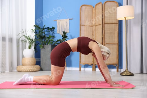 Preview: Mature woman in sportswear stretching on mat at home
