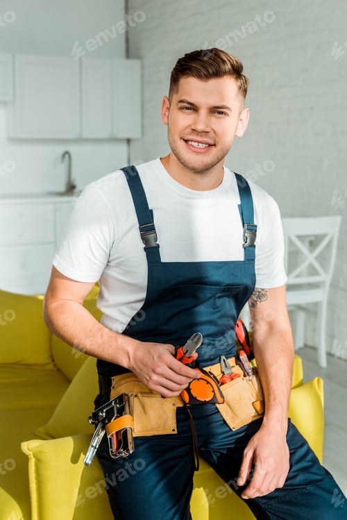 Preview: sunshine on cheerful installer in overalls holding pliers