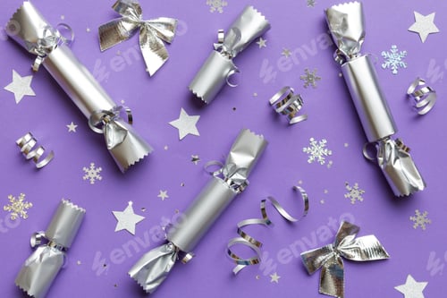 Preview: Christmas crackers with shiny confetti on color background, top view, copy space