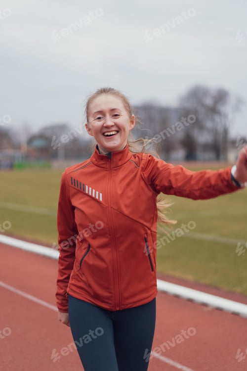 Preview: Portrait of young fitness woman running at a track and field stadium