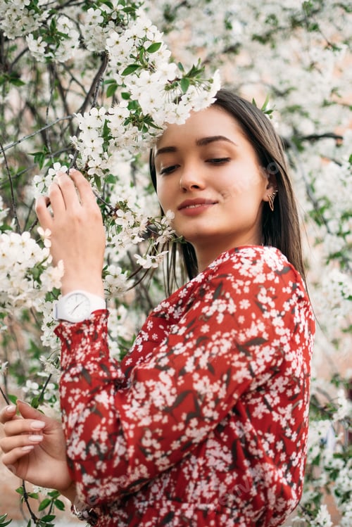 Preview: Beautiful young woman in blooming cherry blossoms garden. Portrait of spring woman in cherry flower