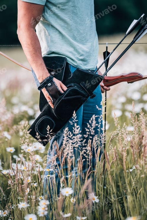 Preview: a man standing in the middle of a field holding a bow and arrows