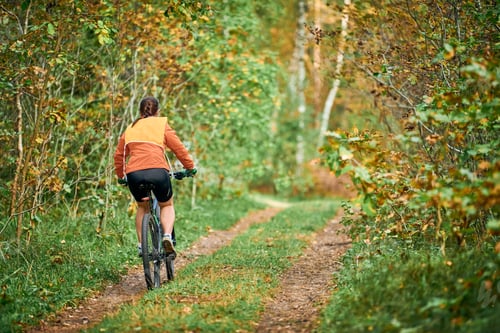 Preview: Female mountain biker riding on bike in nature taking part in competition, sports, fitness, health
