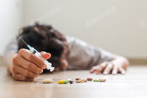 Preview: Unconscious Drug Addict Hands Lying On Grungy Concrete Floor With Pills, Syringe, Cooked Heroine