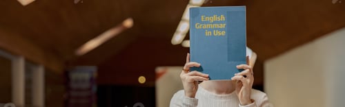 Preview: Young talented female student studying English Grammar while sit in university library
