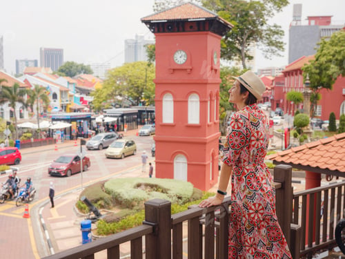 Preview: woman in dress and hat exploring vibrant streets of Malacca, Malaysia.