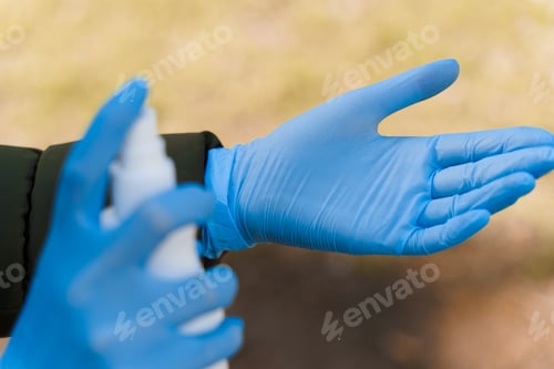 Preview: Hands in blue gloves disinfected with antiseptic. SARS CoV-2 prevention. Cleaning hands