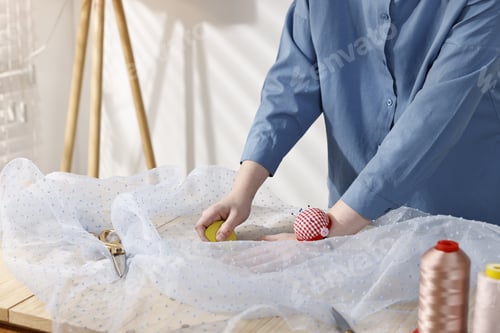 Preview: Woman marking fabric with chalk at table in workshop, closeup