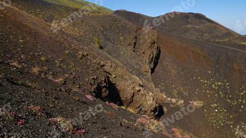 Preview: Dramatic, stark landscape on slopes of volcano, featuring dark, barren lava rock and volcanic ash.