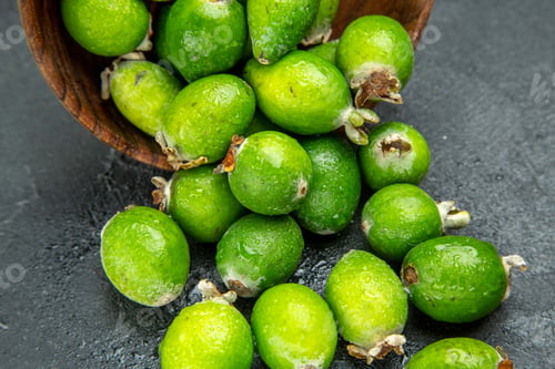 Preview: High reolution photo of natural fresh green feijoas fallen from a small brown pot on dark