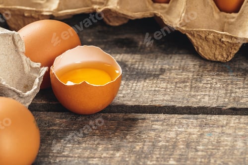 Preview: egg is half broken on wooden table