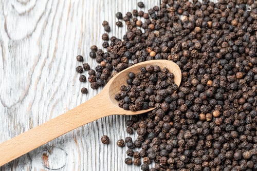 Preview: Pile of Black Peppercorns with a Wooden Spoon