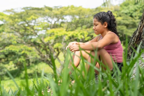 Preview: latina brunette girl sitting on a tree trunk with a worried and bored face. very thoughtful
